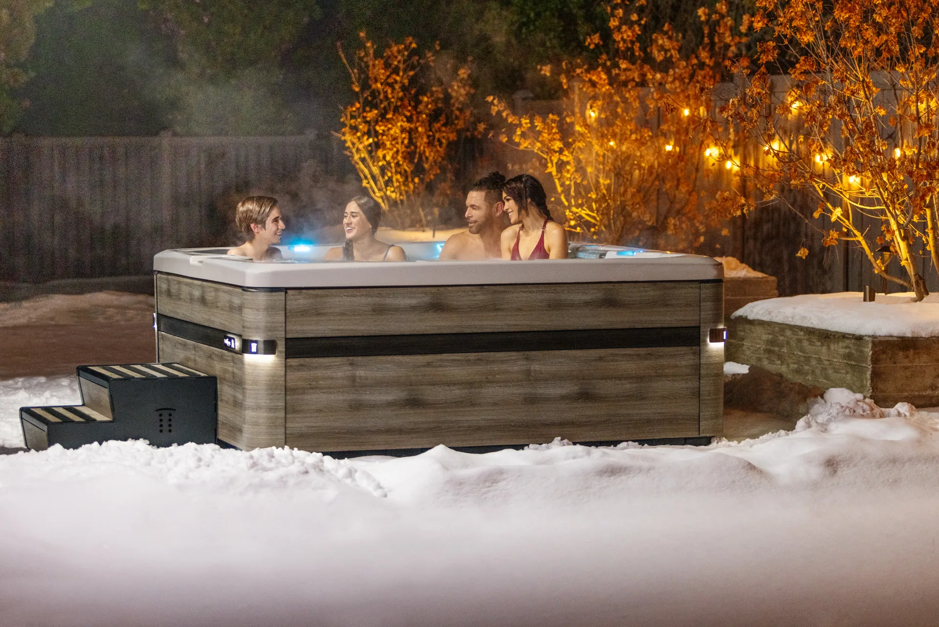 Freunde entspannen abends im Whirlpool im Schnee