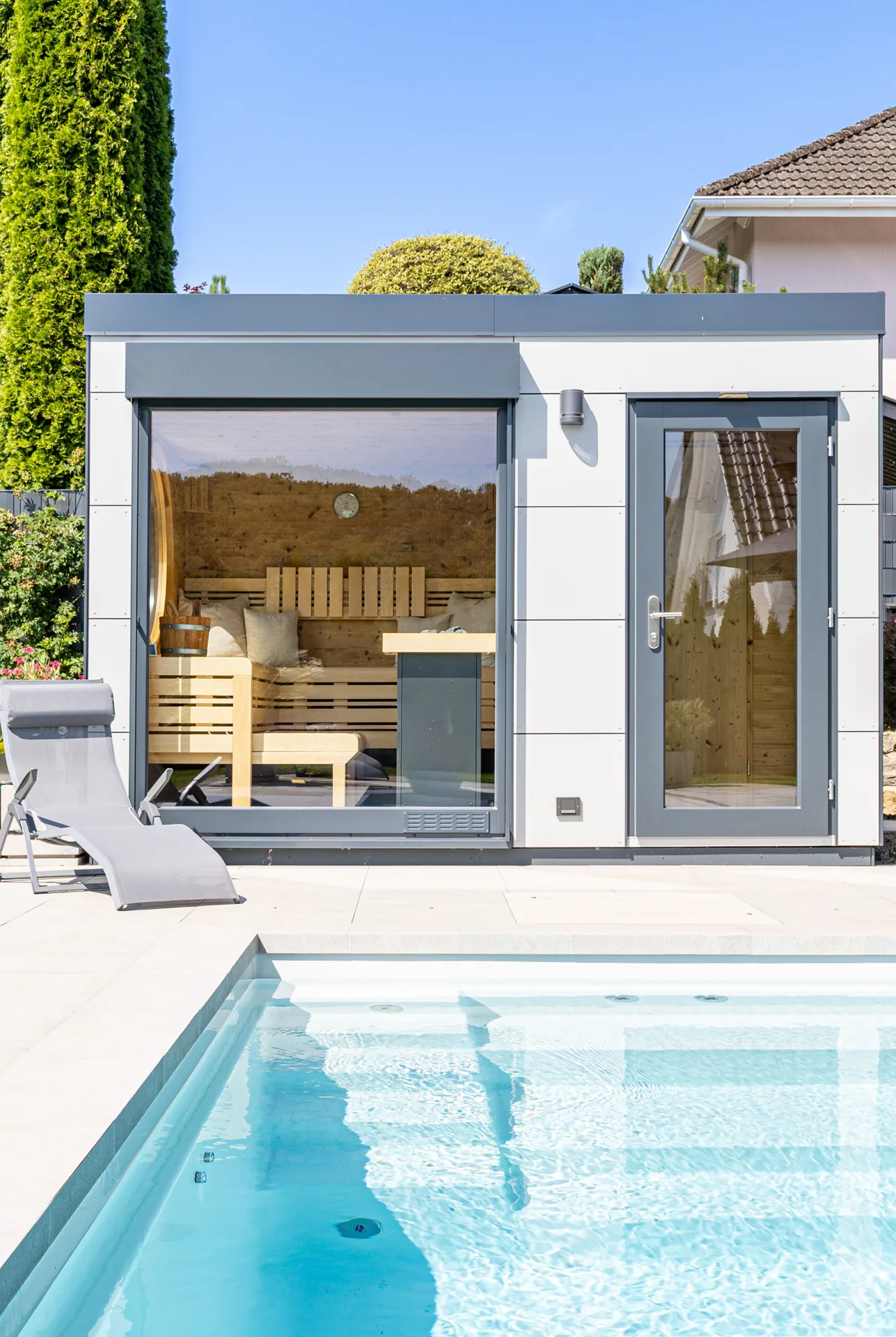 Gartensauna mit Glasfront neben einem Pool