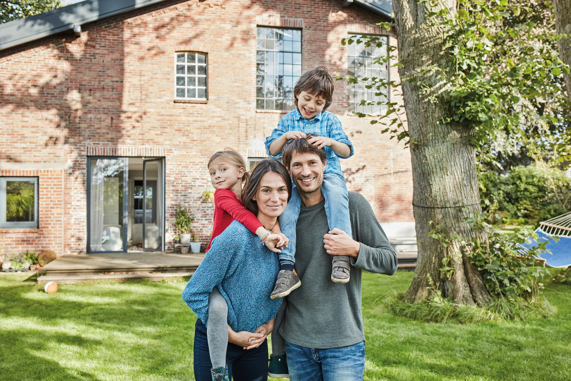 Familie mit zwei Kindern vor ihrem Backsteinhaus