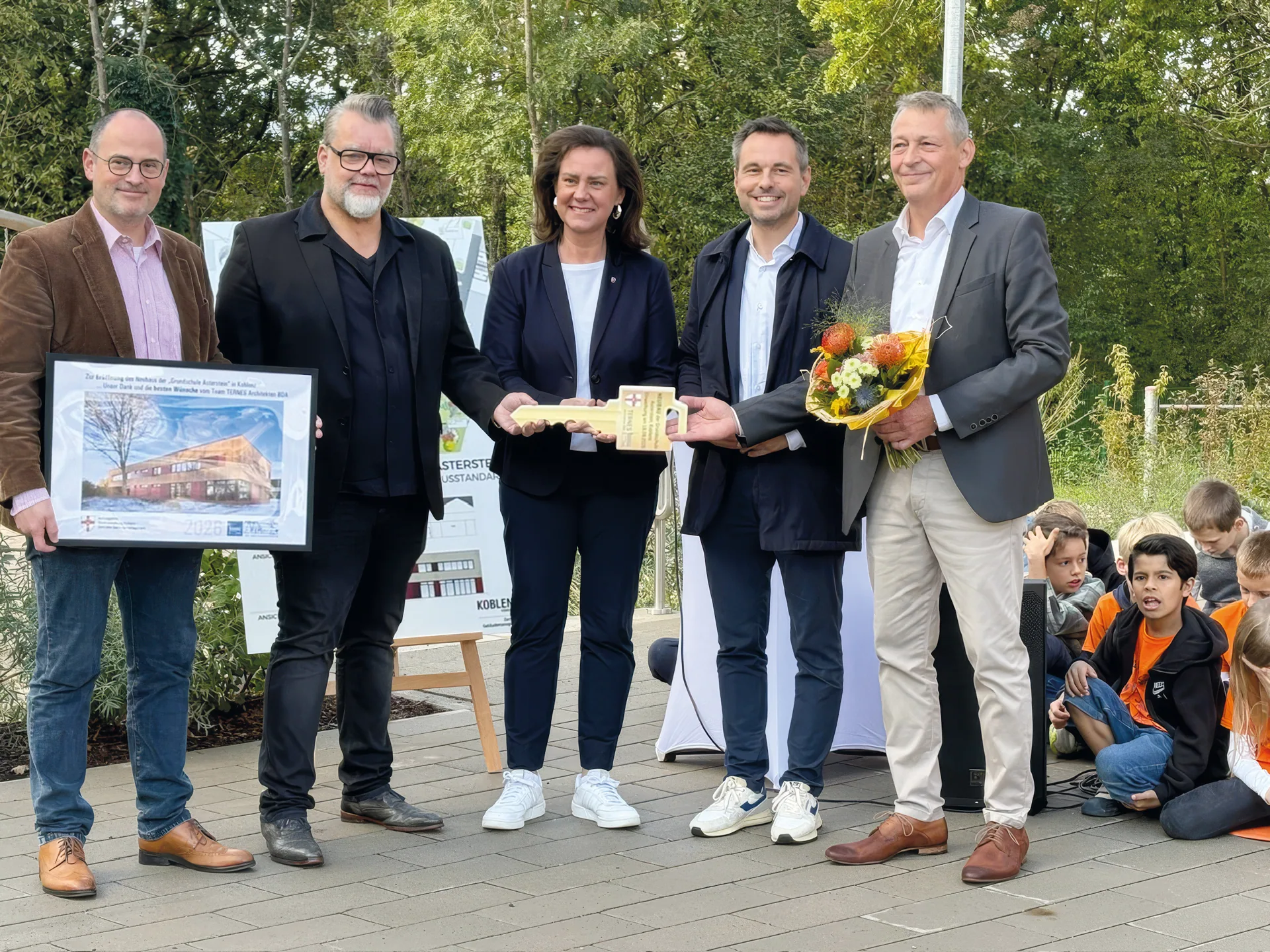 Oberb&uuml;rgermeister David Langner, Ministerin Dr. Ute Eiling-H&uuml;tig, Architekt Jens J. Ternes und weitere G&auml;ste bei der Schl&uuml;ssel&uuml;bergabe an der Grundschule Asterstein