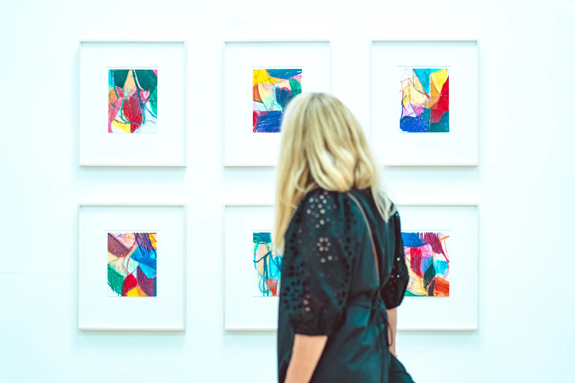 Besucherin vor farbigen Bildern in einer Galerie